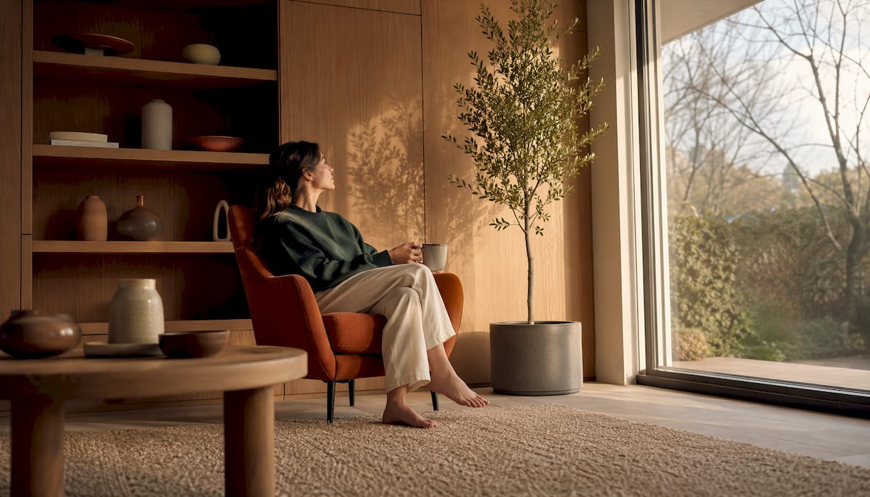 Eine Frau richtet im gemütlichen Wohnzimmer einen künstlichen Baum her.
